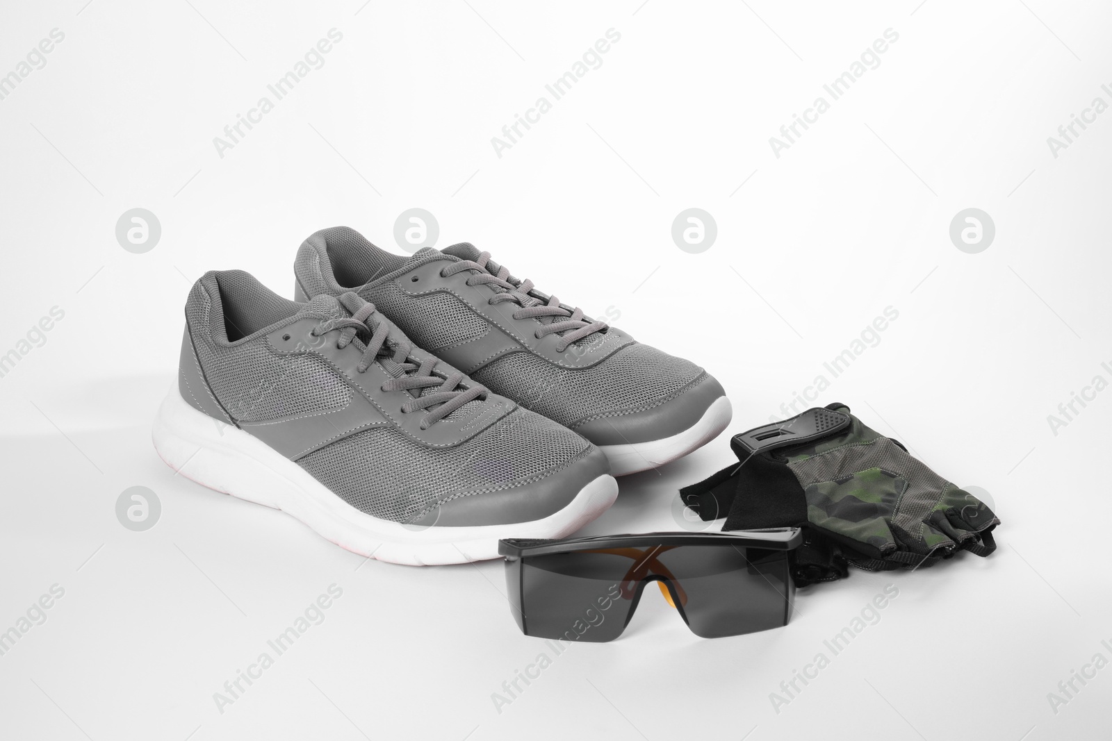 Photo of Gray sneakers, fingerless cycling gloves and goggles isolated on white