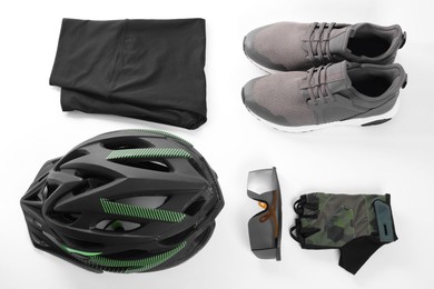 Photo of Bicycle helmet, sportswear and sneakers on white background, flat lay