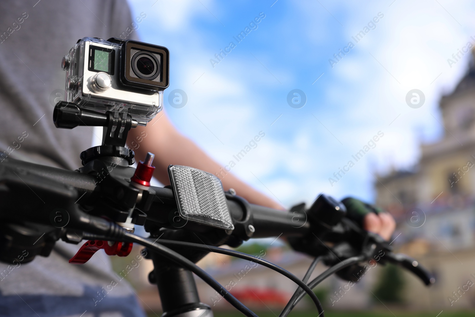 Photo of Man riding bicycle with modern action camera outdoors, closeup