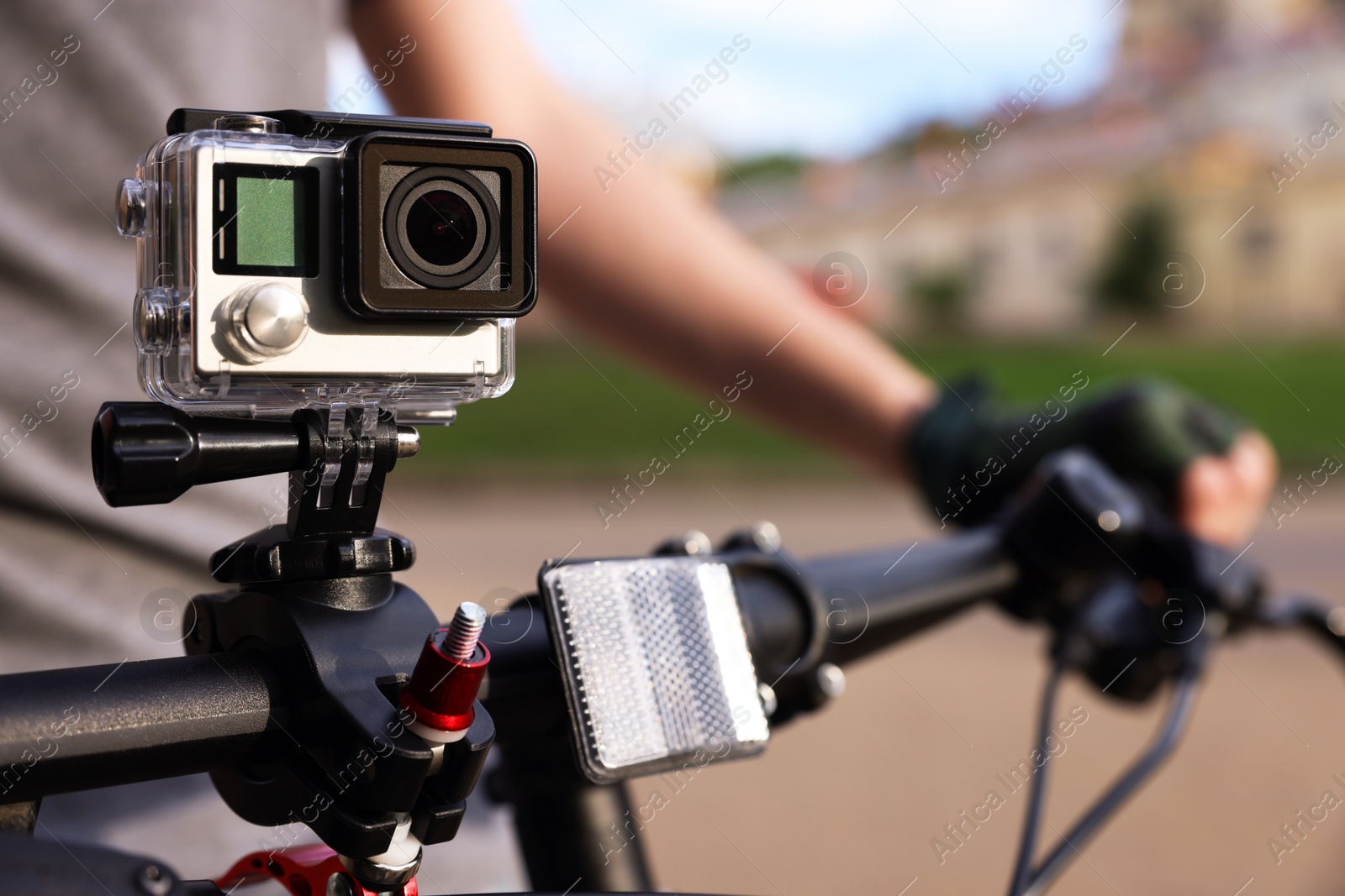 Photo of Man riding bicycle with modern action camera outdoors, closeup