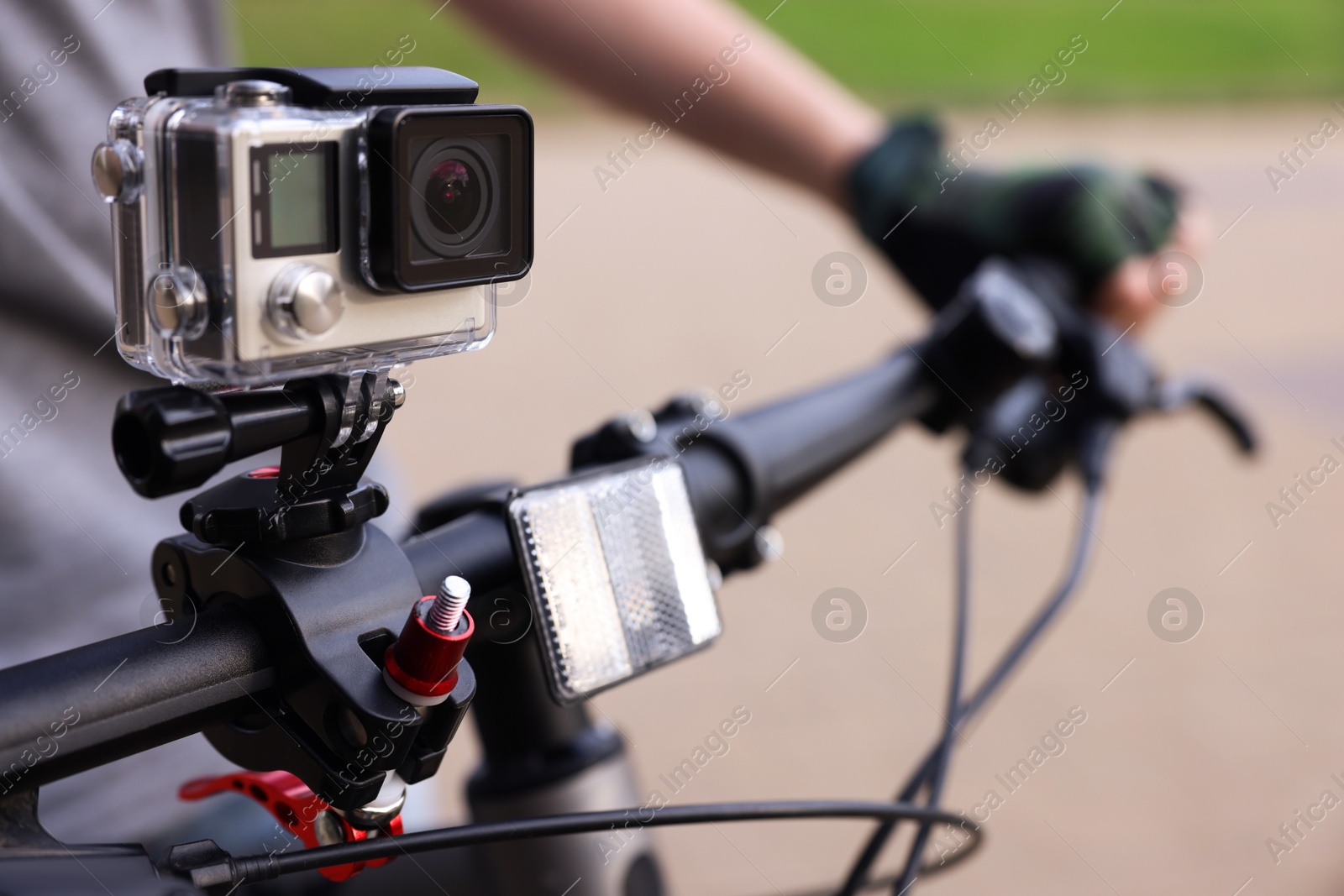 Photo of Man riding bicycle with modern action camera outdoors, closeup