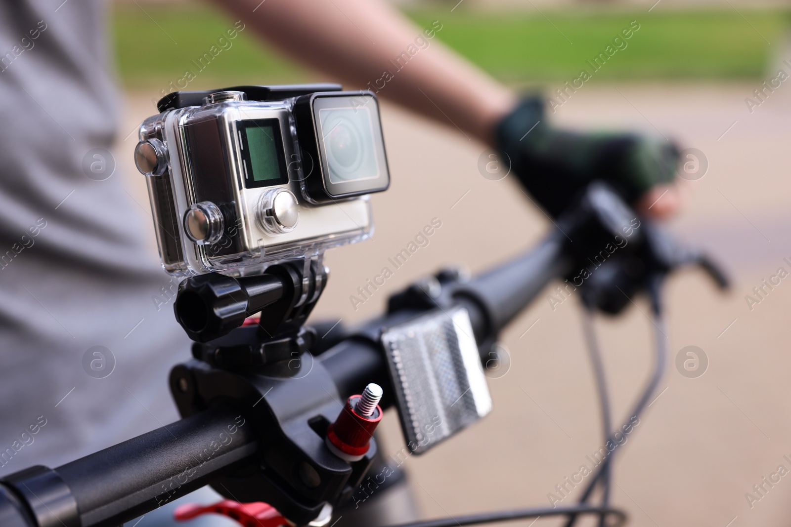 Photo of Man riding bicycle with modern action camera outdoors, closeup