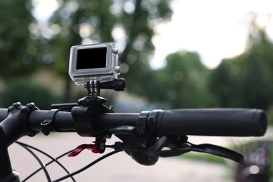 Modern action camera with mount on bicycle outdoors, closeup