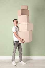 Moving into new house. Man with cardboard boxes near light green wall