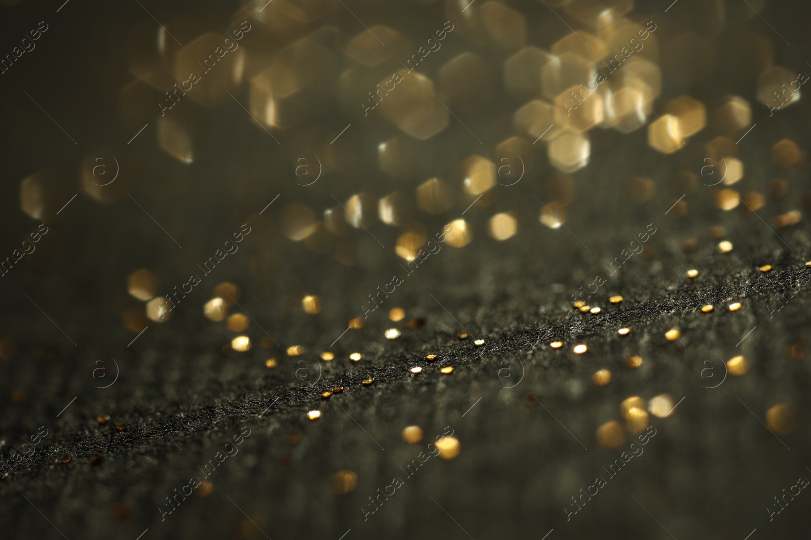 Photo of Beautiful shiny golden glitter on black background, closeup