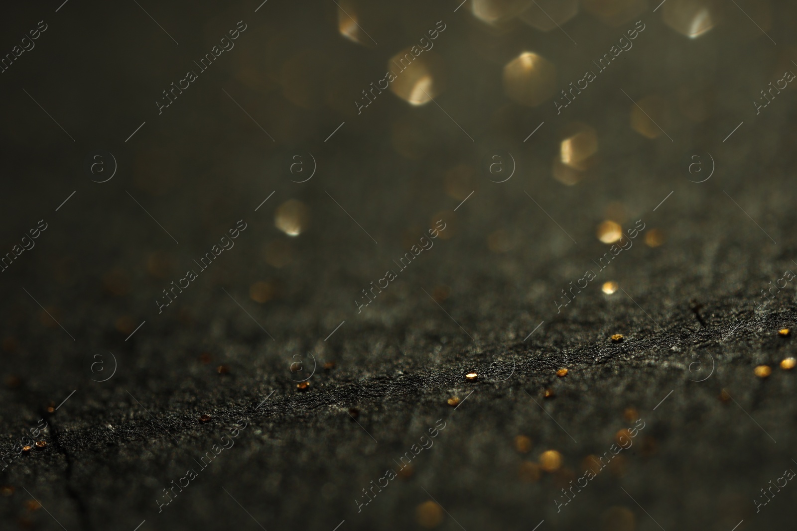 Photo of Beautiful shiny golden glitter on black background, closeup