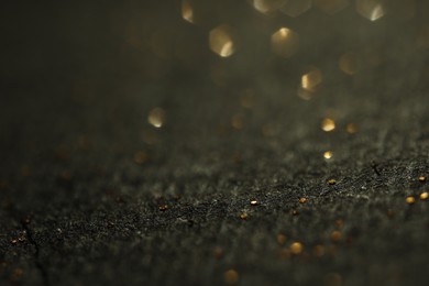 Photo of Beautiful shiny golden glitter on black background, closeup