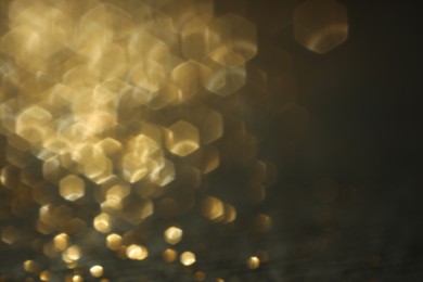 Photo of Beautiful shiny golden glitter on black background, closeup