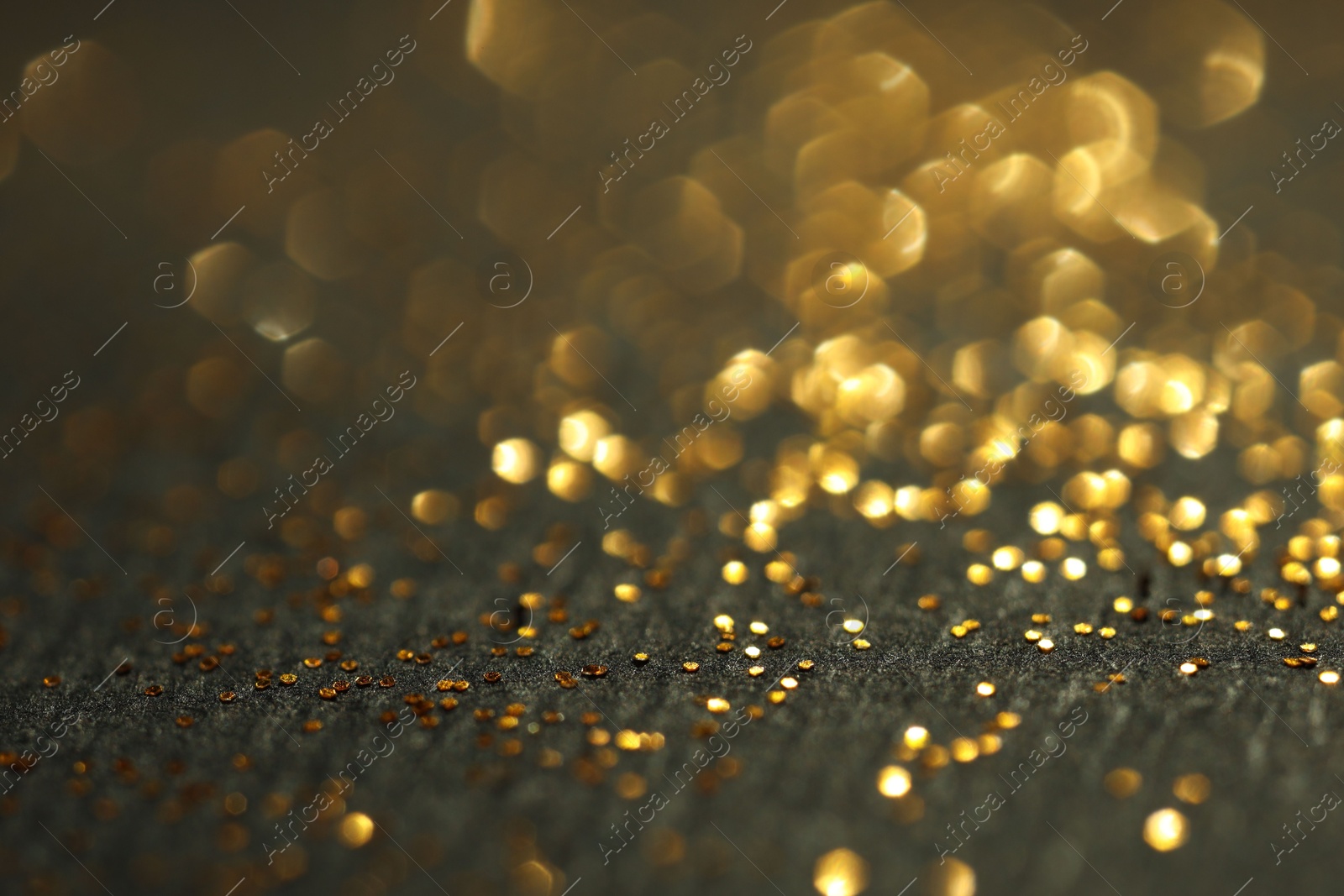 Photo of Beautiful shiny golden glitter on black background, closeup