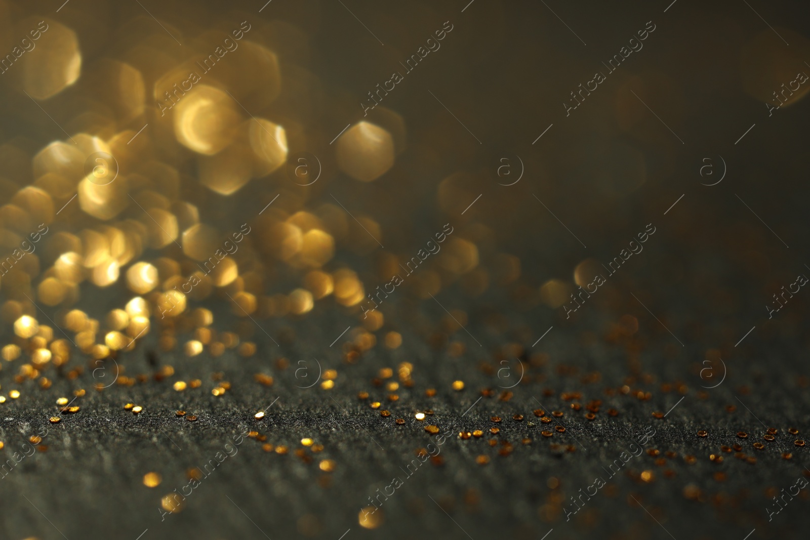 Photo of Beautiful shiny golden glitter on black background, closeup