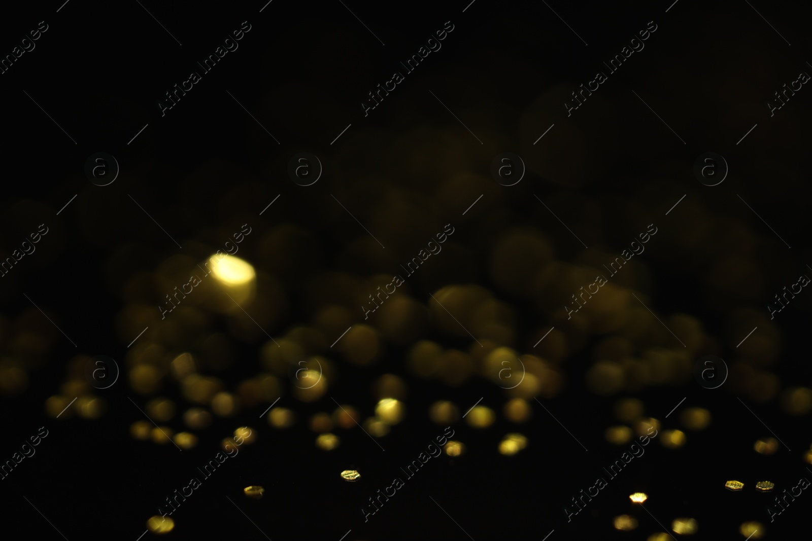 Photo of Beautiful shiny golden glitter on black background, closeup