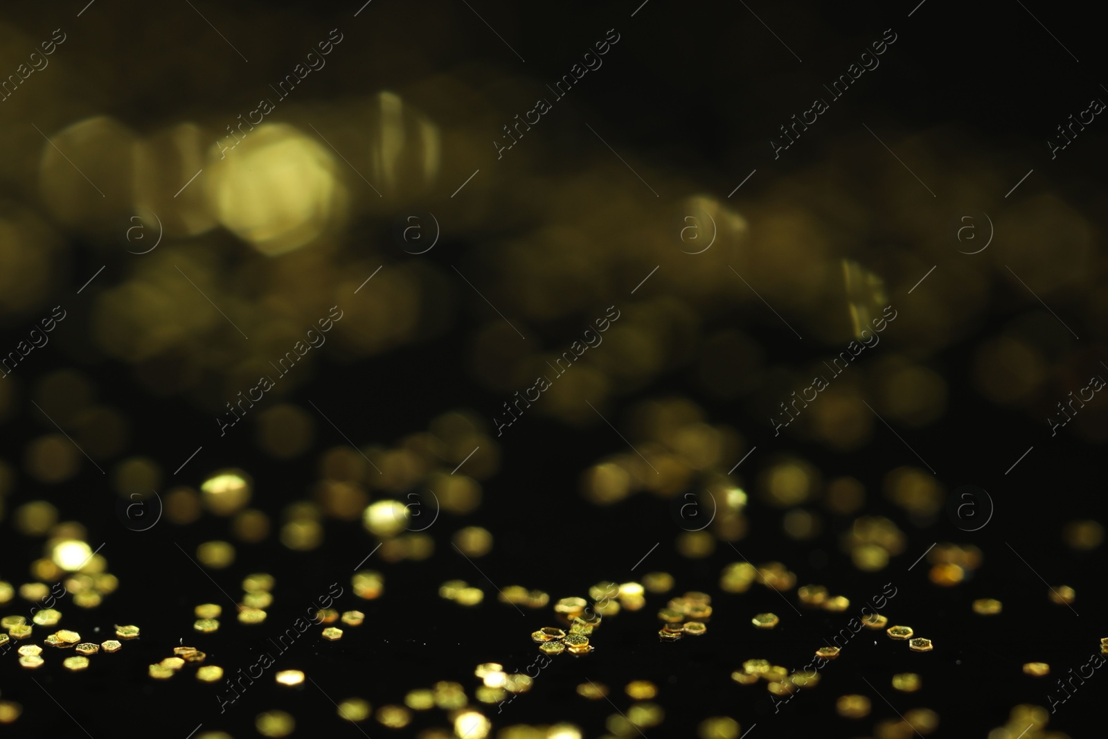 Photo of Beautiful shiny golden glitter on black background, closeup