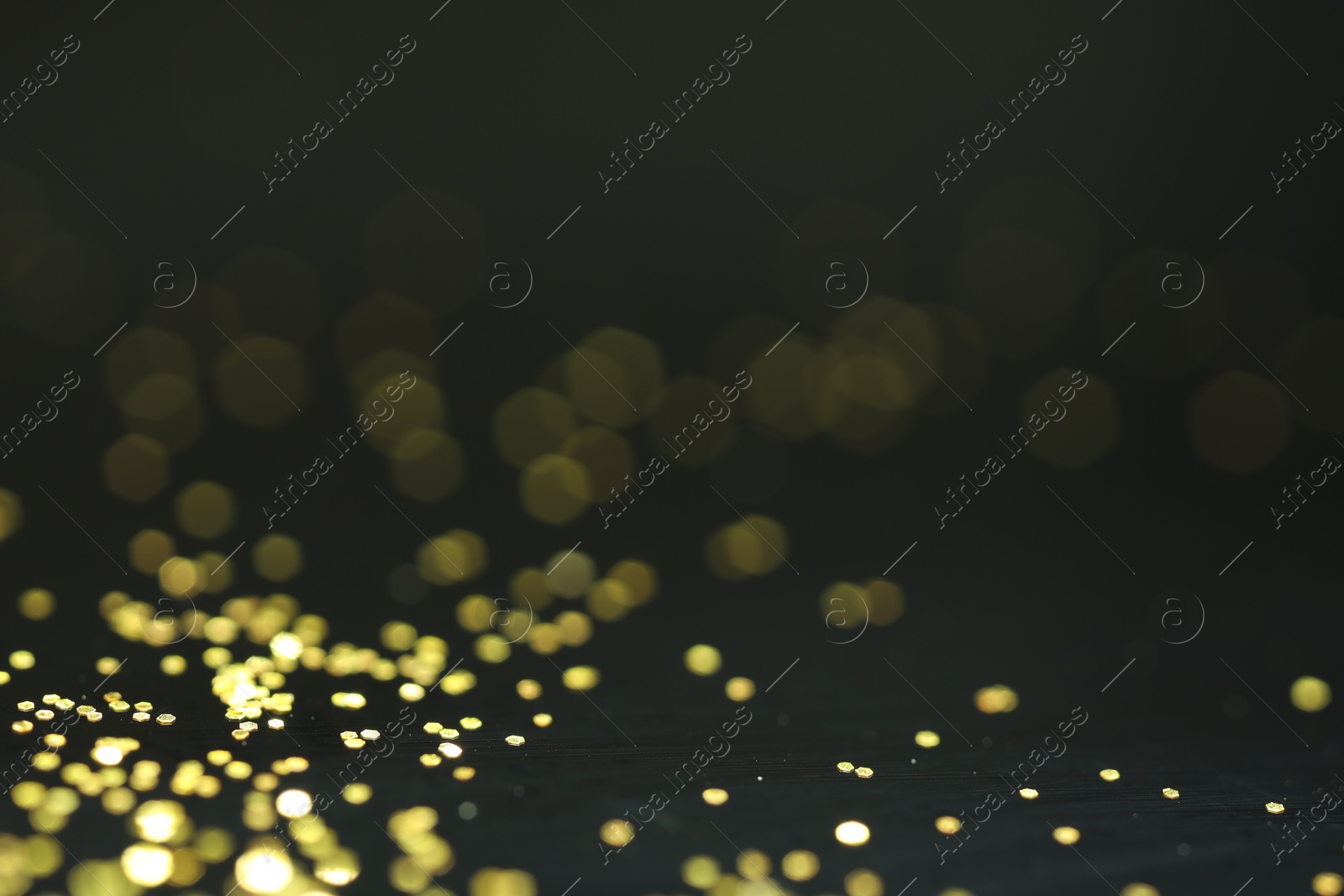 Photo of Beautiful shiny golden glitter on black background, closeup