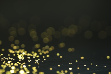 Photo of Beautiful shiny golden glitter on black background, closeup