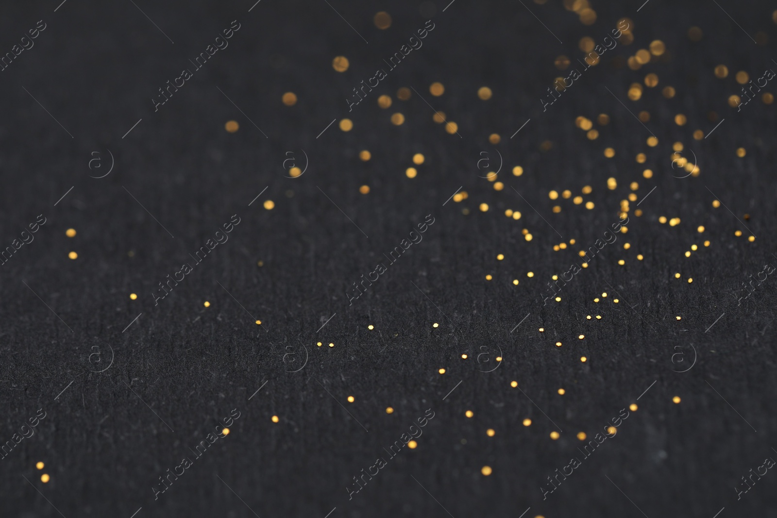 Photo of Beautiful shiny golden glitter on black background, closeup