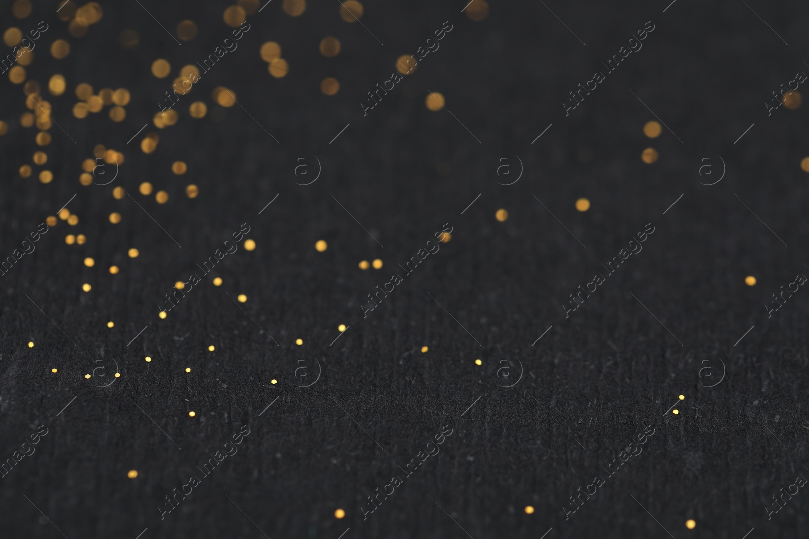 Photo of Beautiful shiny golden glitter on black background, closeup