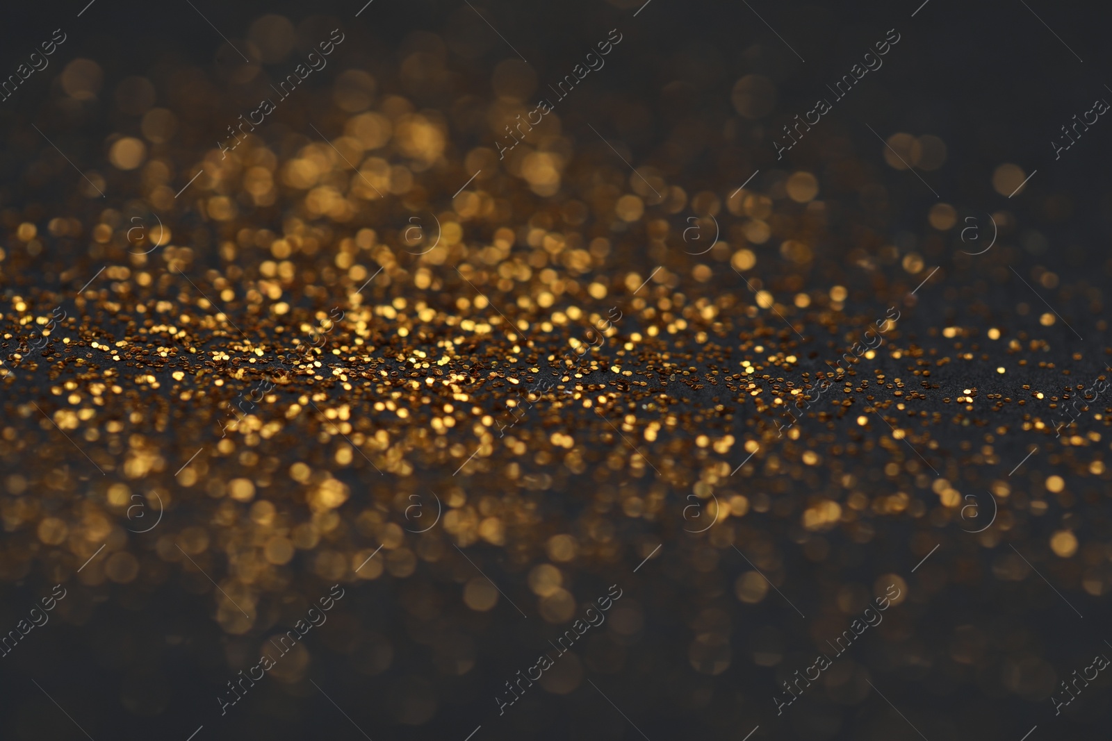 Photo of Beautiful shiny golden glitter on black background, closeup