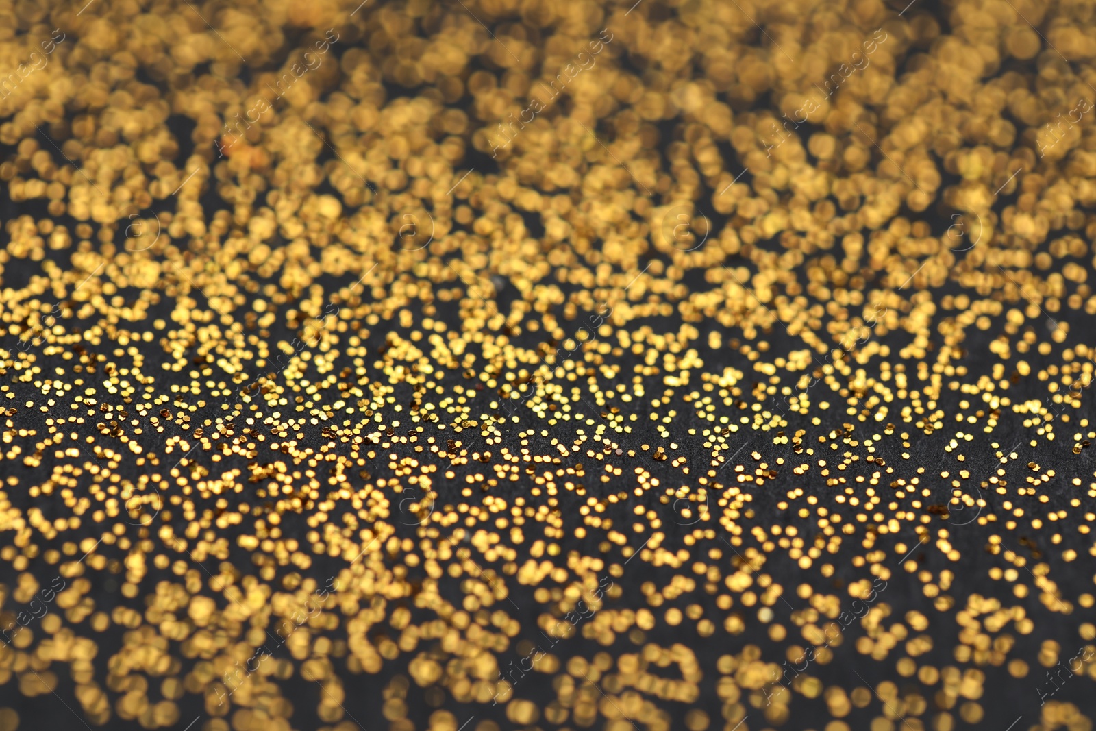 Photo of Beautiful shiny golden glitter on black background, closeup