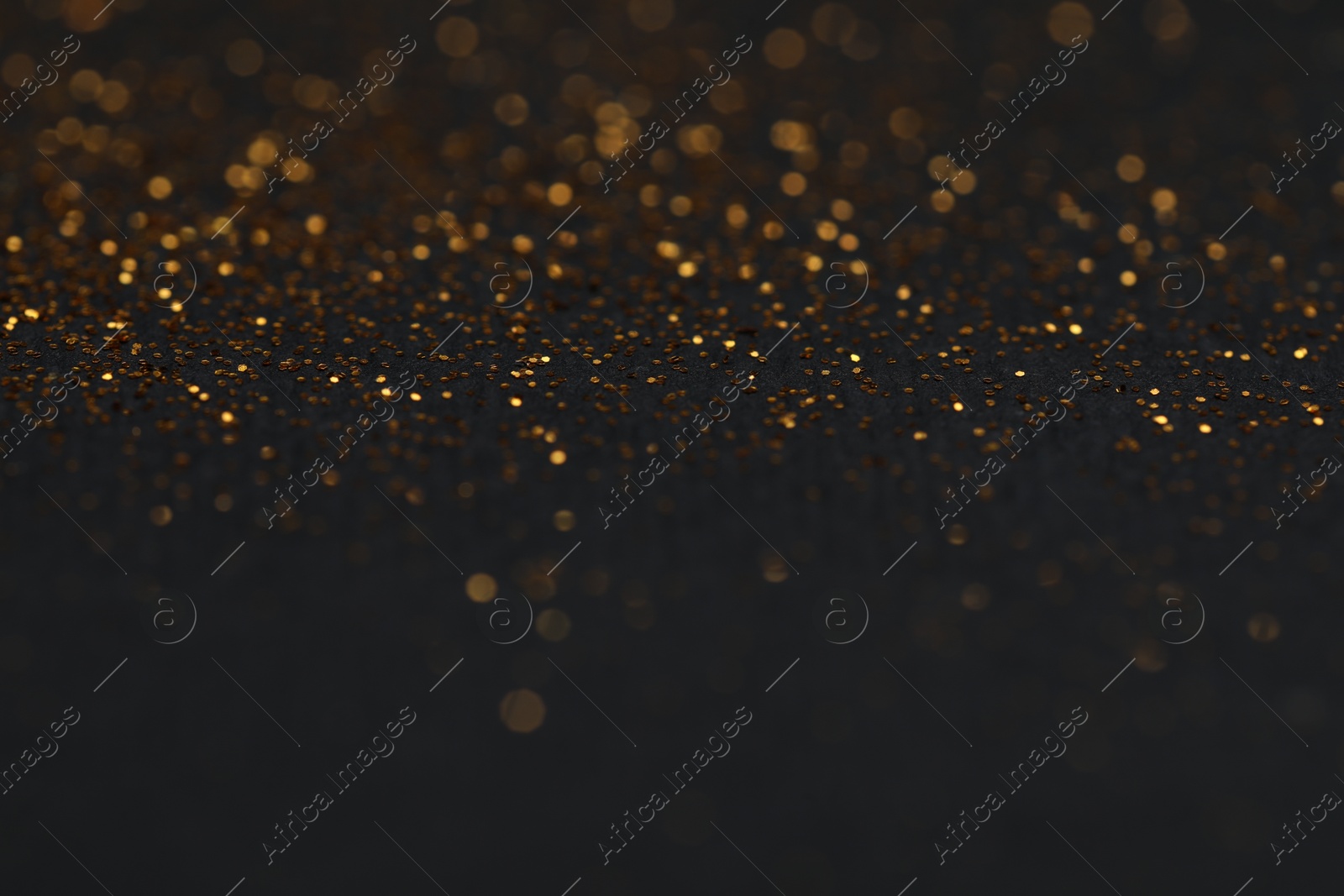 Photo of Beautiful shiny golden glitter on black background, closeup