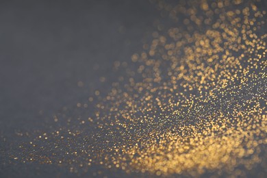 Photo of Beautiful shiny golden glitter on black background, closeup