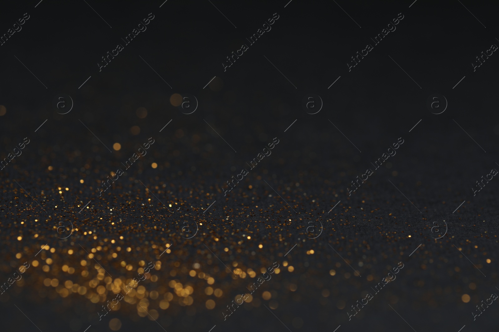 Photo of Beautiful shiny golden glitter on black background, closeup