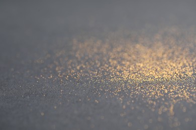 Photo of Beautiful shiny golden glitter on black background, closeup