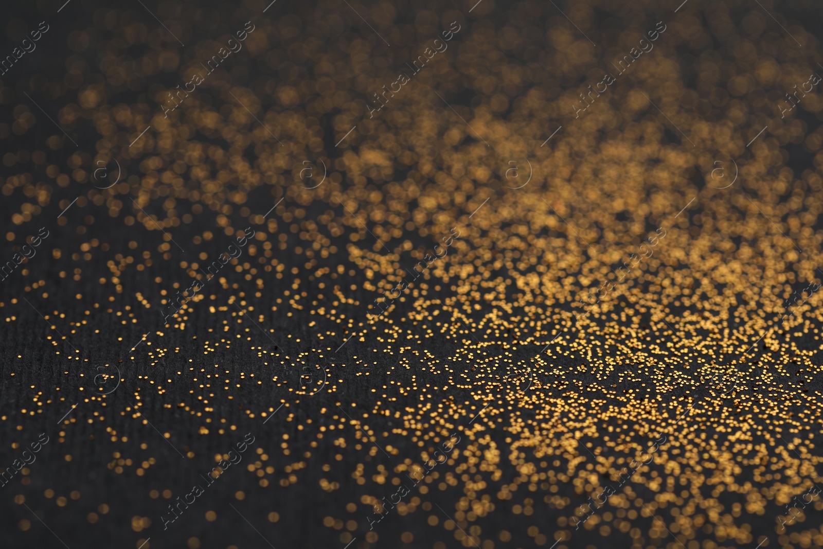 Photo of Beautiful shiny golden glitter on black background, closeup