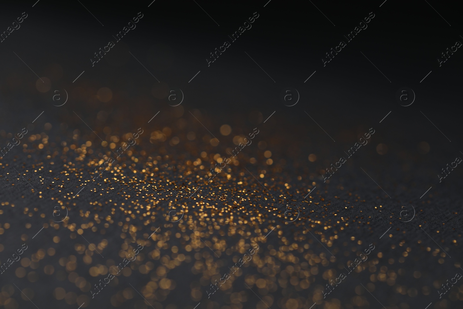 Photo of Beautiful shiny golden glitter on black background, closeup