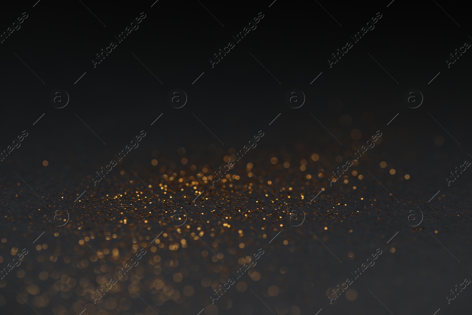 Photo of Beautiful shiny golden glitter on black background, closeup