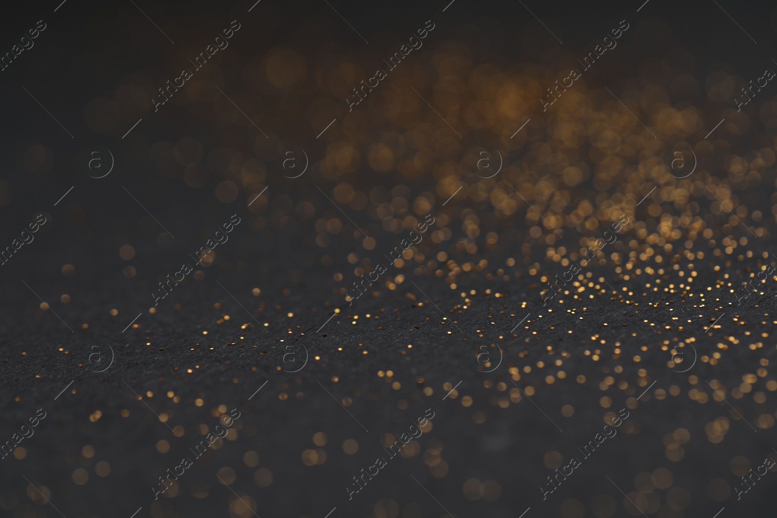 Photo of Beautiful shiny golden glitter on black background, closeup