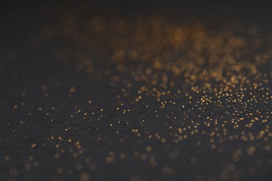 Photo of Beautiful shiny golden glitter on black background, closeup