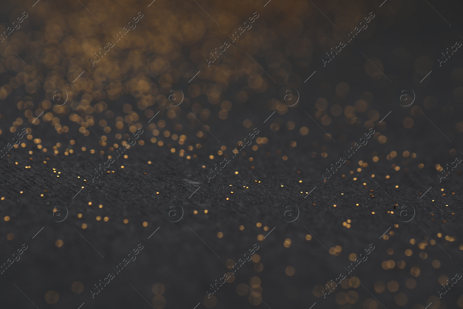 Photo of Beautiful shiny golden glitter on black background, closeup