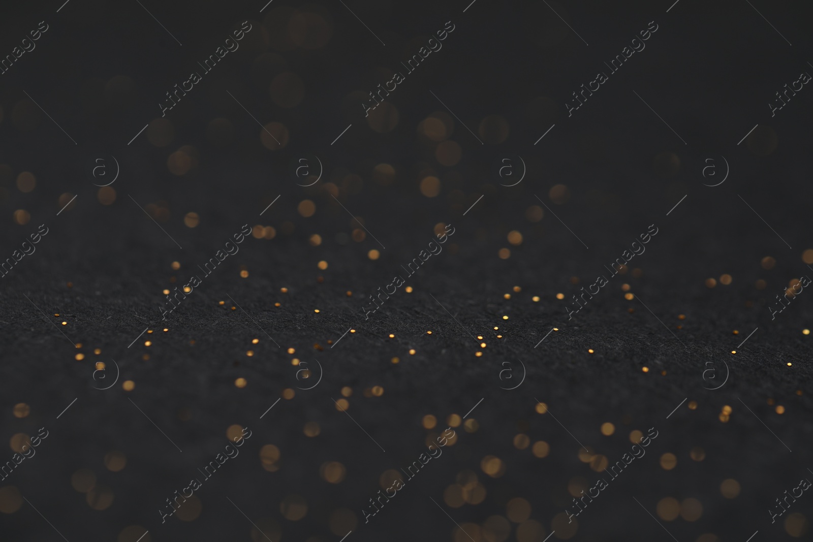 Photo of Beautiful shiny golden glitter on black background, closeup