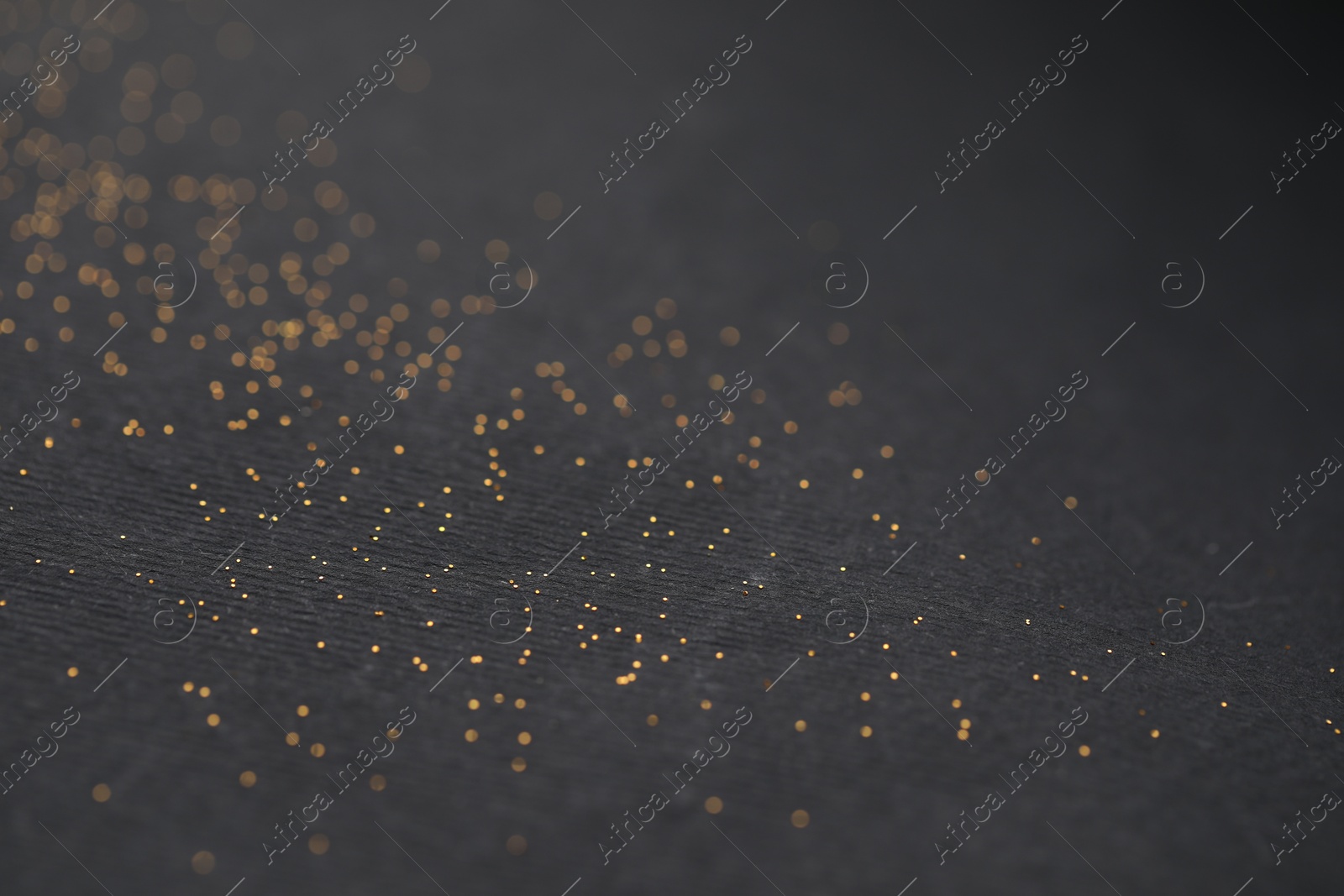 Photo of Beautiful shiny golden glitter on black background, closeup