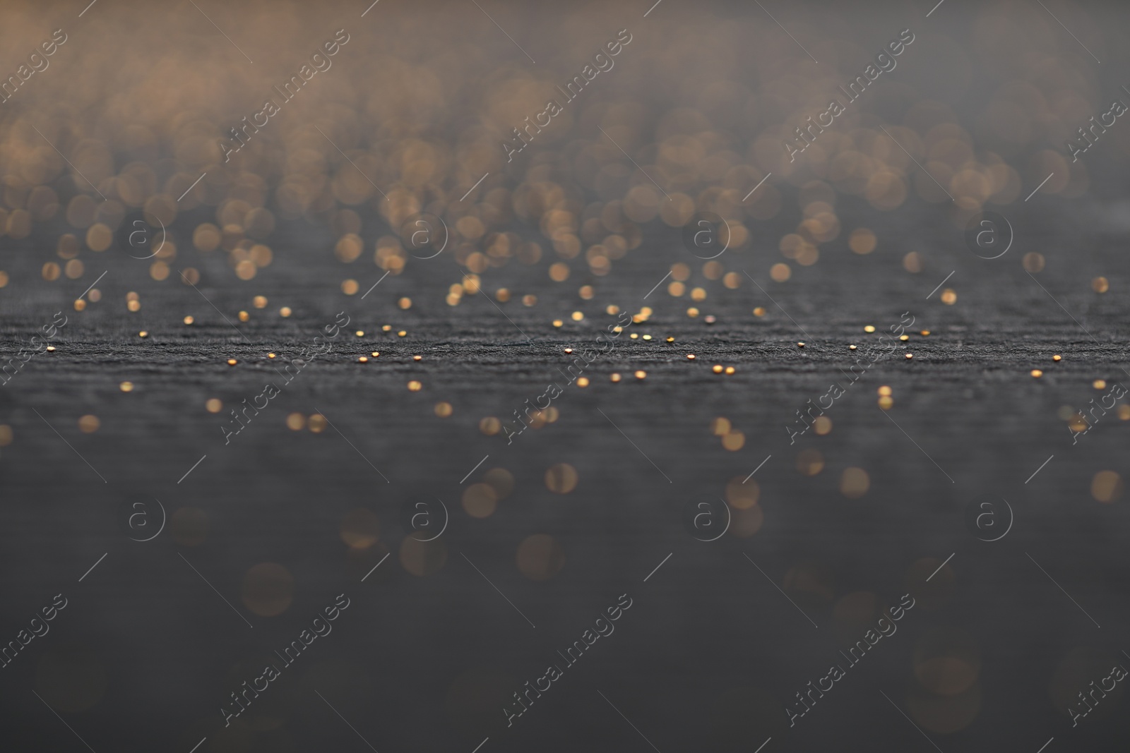 Photo of Beautiful shiny golden glitter on black background, closeup