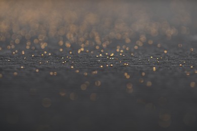 Photo of Beautiful shiny golden glitter on black background, closeup