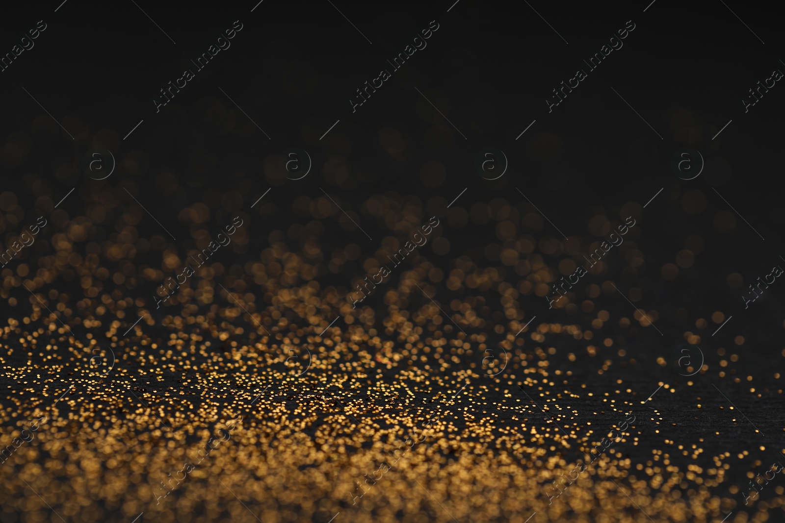 Photo of Beautiful shiny golden glitter on black background, closeup