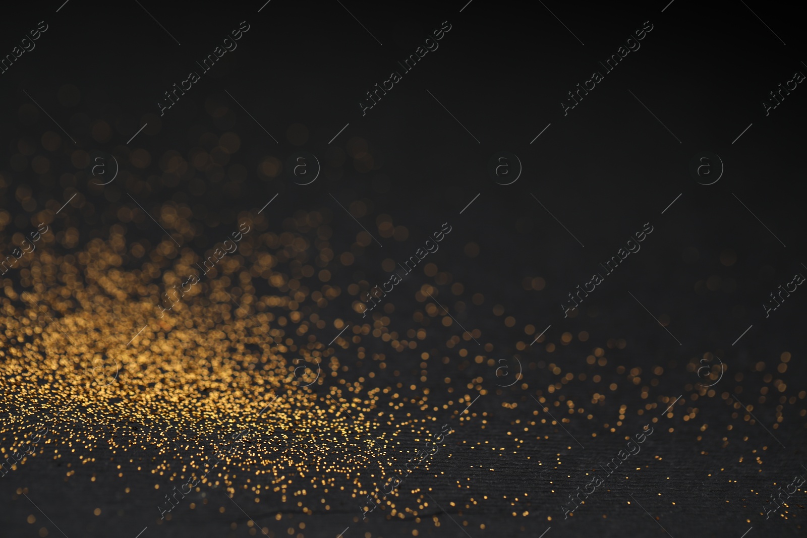 Photo of Beautiful shiny golden glitter on black background, closeup