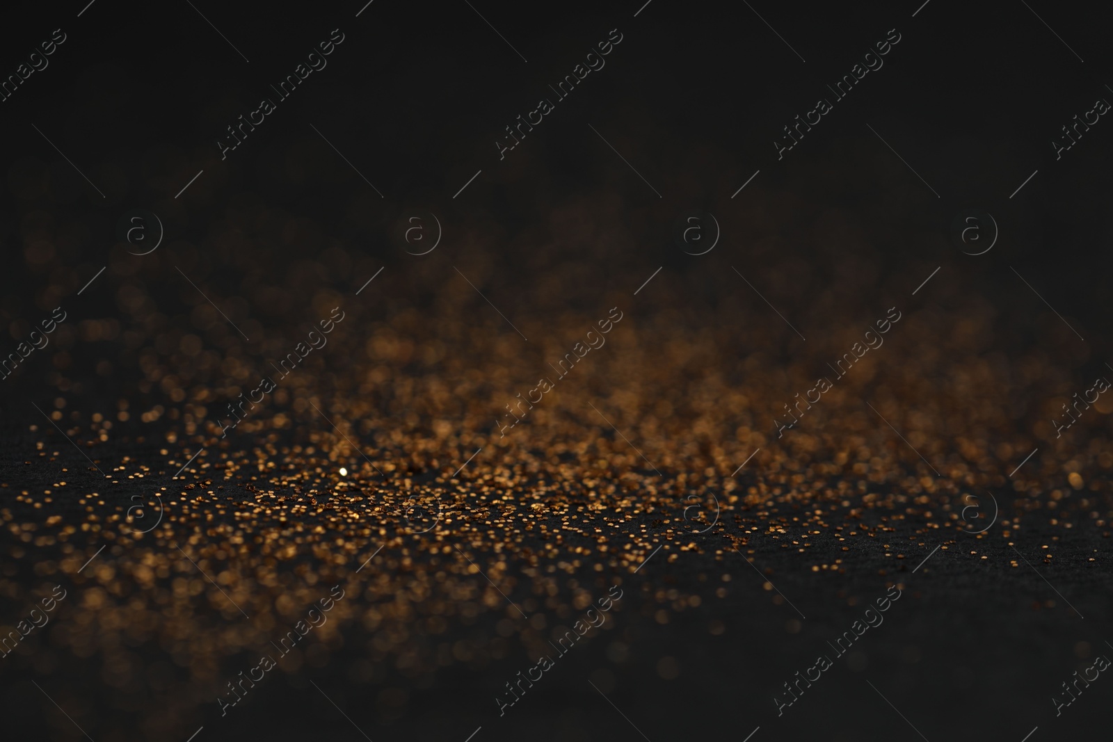 Photo of Beautiful shiny golden glitter on black background, closeup