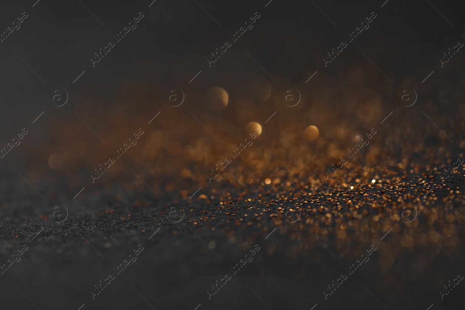 Photo of Beautiful shiny golden glitter on black background, closeup