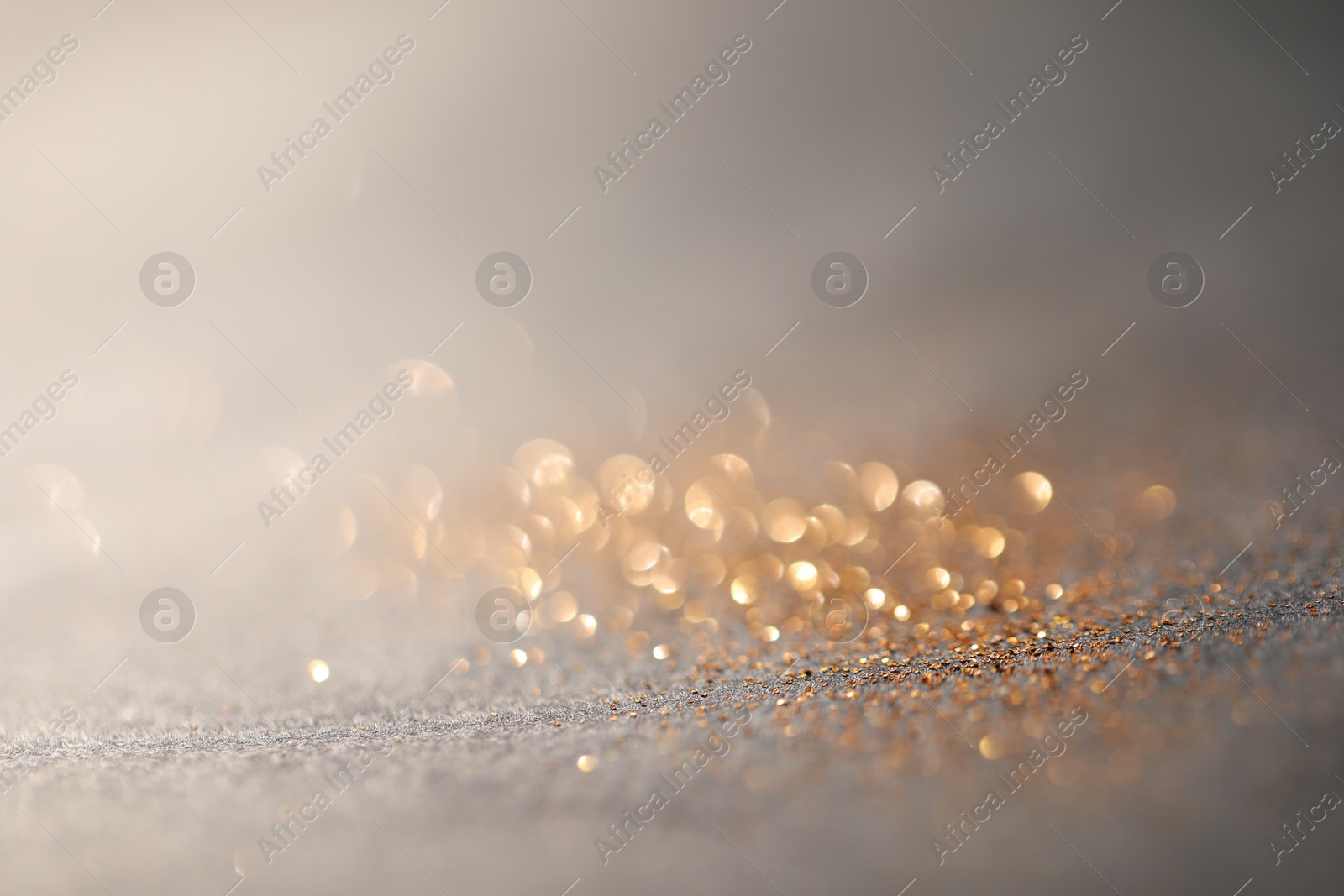 Photo of Beautiful shiny glitter on grey background, closeup