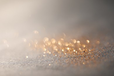 Photo of Beautiful shiny glitter on grey background, closeup