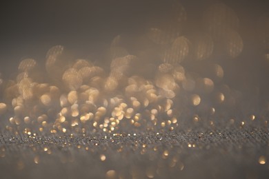 Photo of Beautiful shiny glitter on grey background, closeup