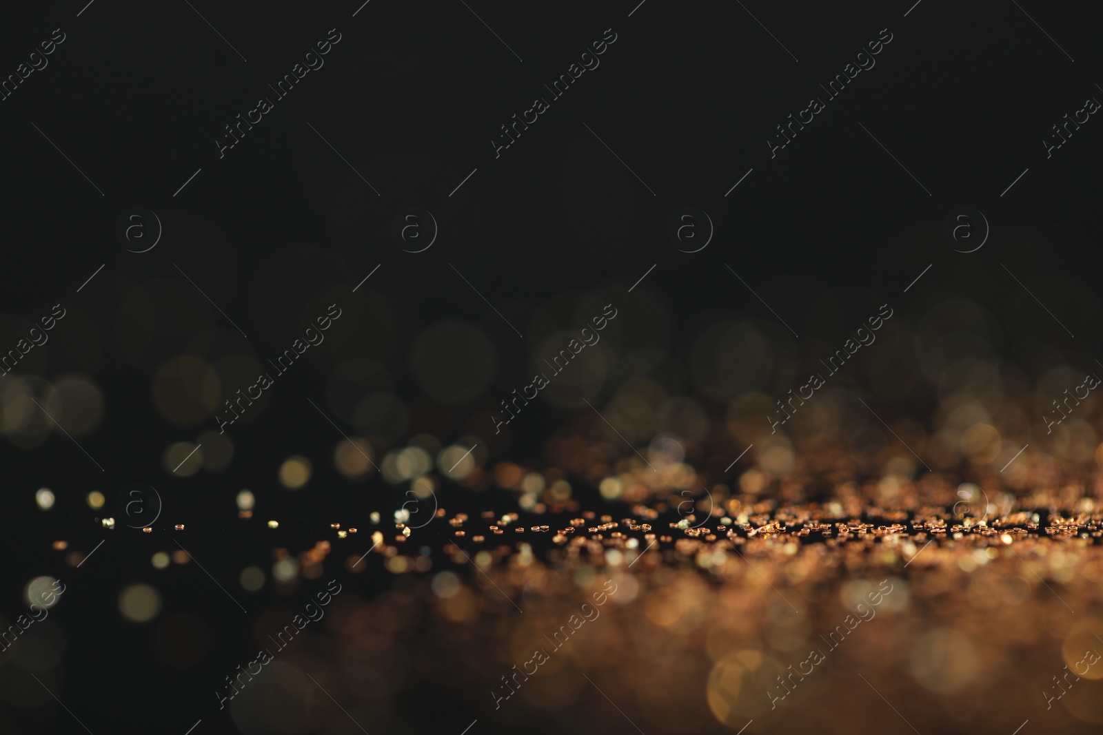 Photo of Beautiful shiny golden glitter on black background, closeup