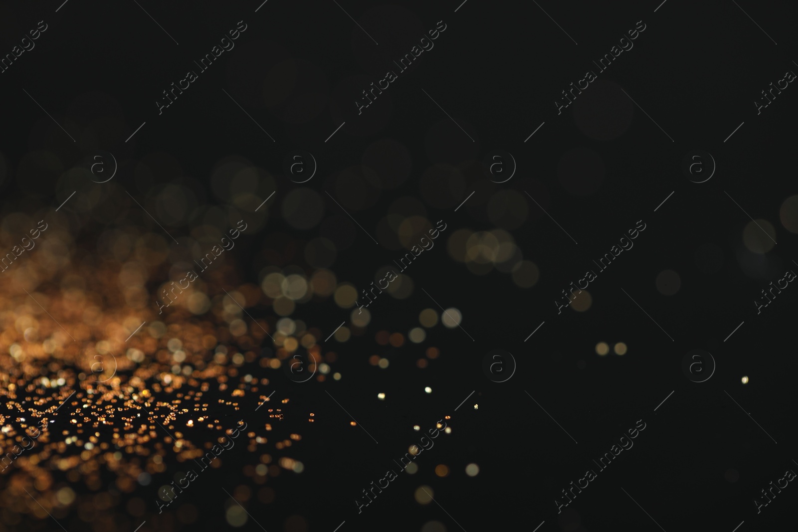 Photo of Beautiful shiny golden glitter on black background, closeup