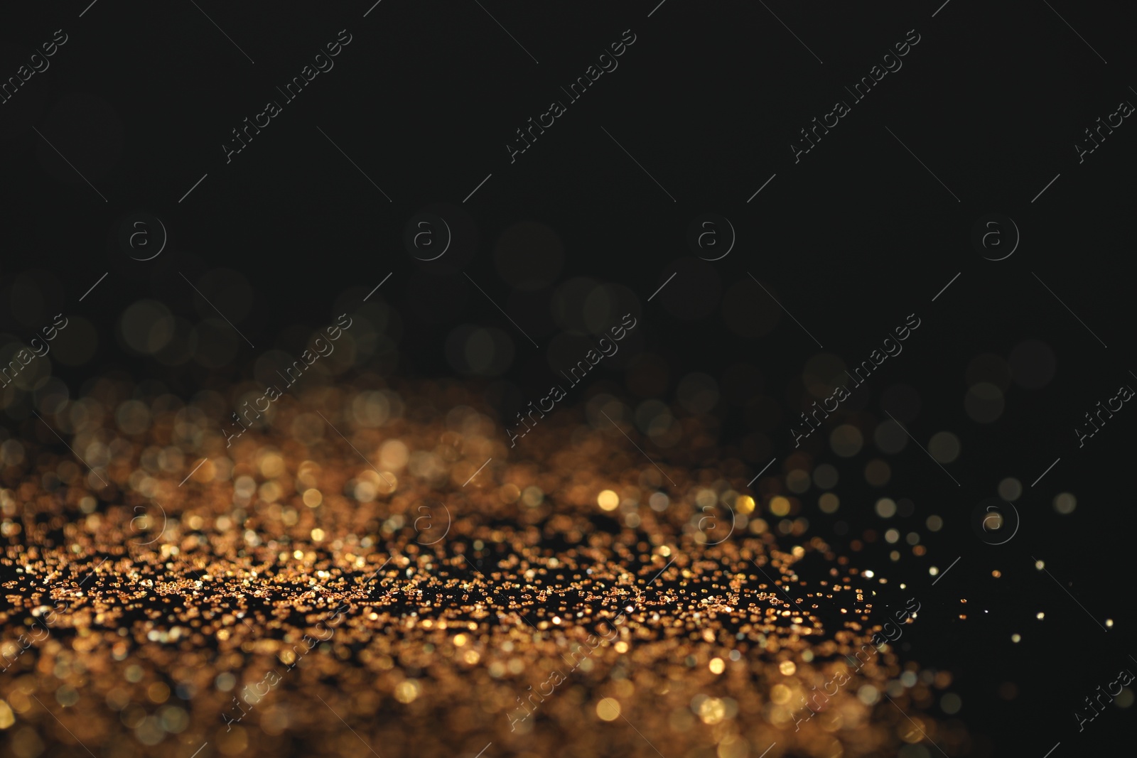 Photo of Beautiful shiny golden glitter on black background, closeup