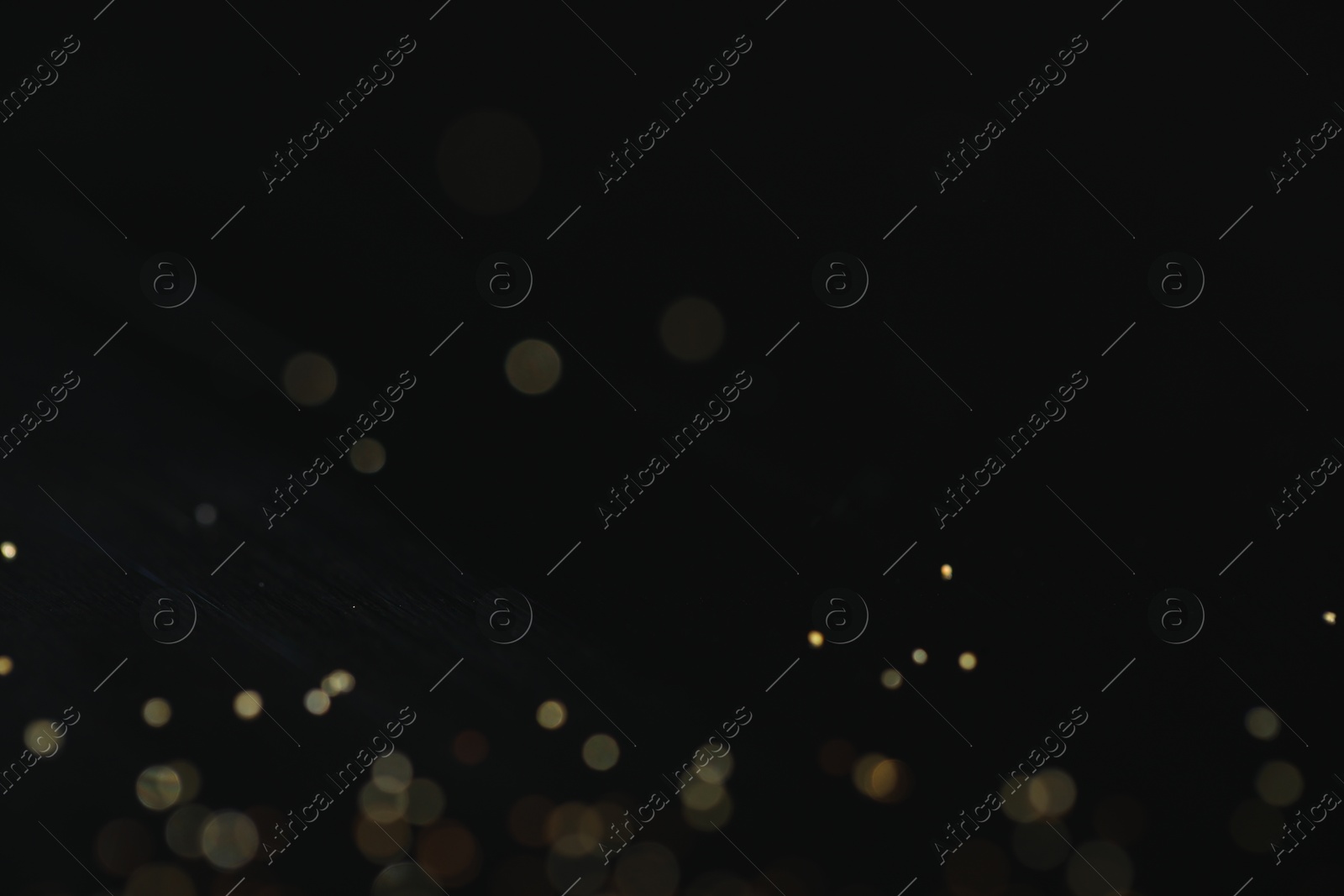 Photo of Beautiful shiny golden glitter on black background, closeup