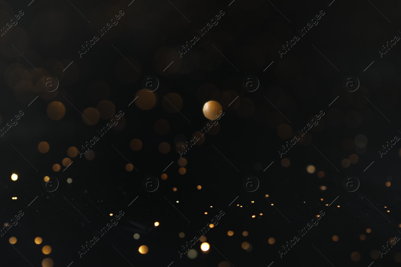 Photo of Beautiful shiny golden glitter on black background, closeup