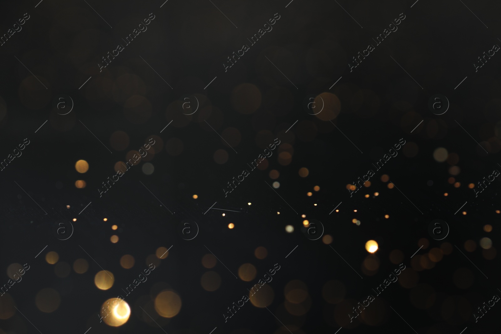 Photo of Beautiful shiny golden glitter on black background, closeup