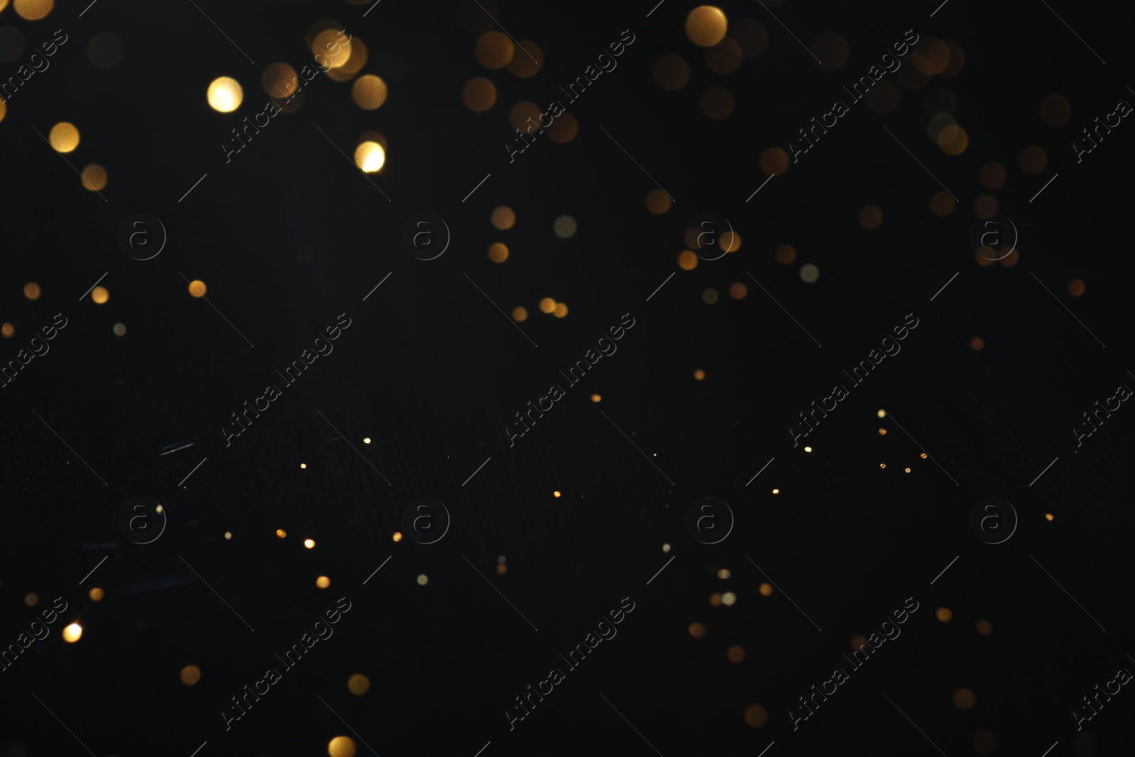 Photo of Beautiful shiny golden glitter on black background, closeup